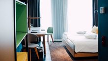 Blick ins Hotelzimmer mit Bett und bunten Regal-Elementen